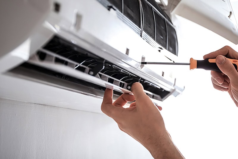 Photo of a person unscrewing a ductless unit.